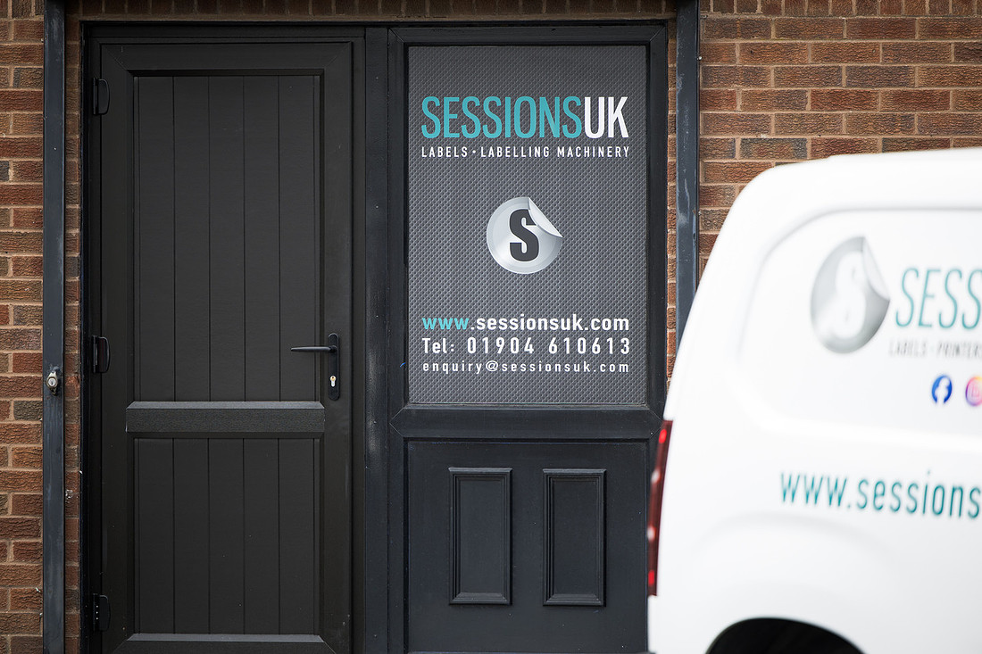 The dark entrance door with the Sessions UK window graphic, the van parked alongside.