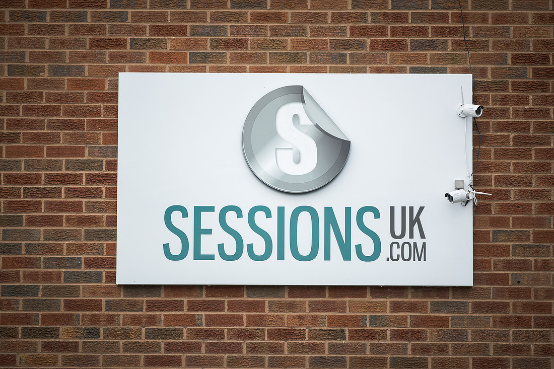 The SESSIONS UK.COM sign mounted flat on the brick wall.